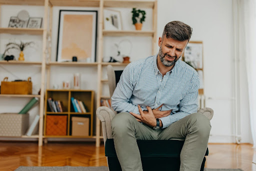 Man Experiencing Discomfort While Seated in a Modern Living Space